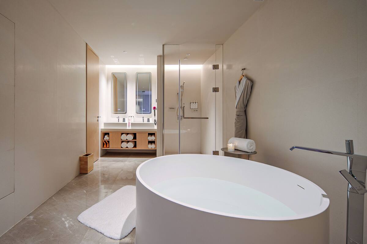 Une salle de bain moderne avec une grande baignoire sur pieds, une douche à parois de verre et un meuble-lavabo avec un miroir.