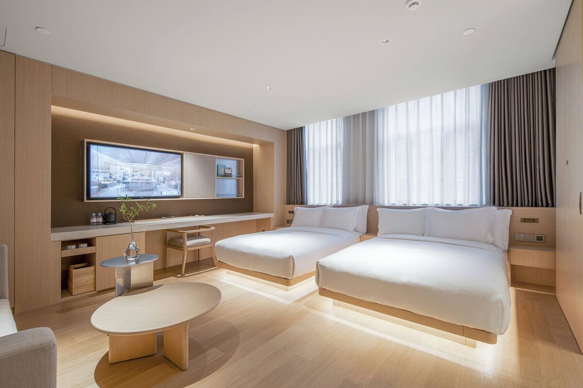 Une chambre d’hôtel moderne équipée de deux lits, d’un bureau, d’une télévision et d’une table à manger.