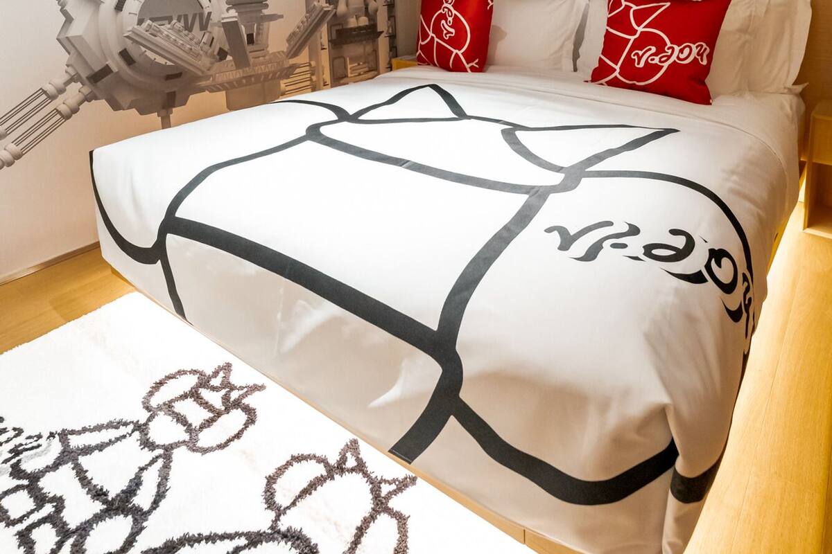 Une chambre d’hôtel avec un lit, une grande fresque murale et un tapis.