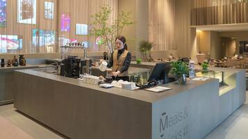 Un mostrador de recepción moderno con una máquina de café, una planta y una pizarra de menú.
