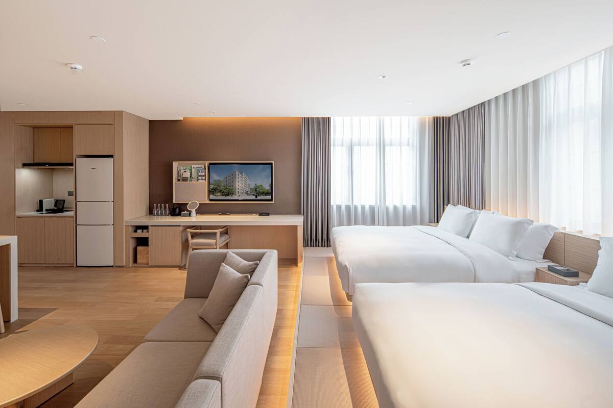 Une chambre d’hôtel équipée d’une kitchenette, d’un canapé, d’un lit et d’une télévision.