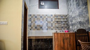 Une salle de bain avec un mur recouvert de carreaux, un meuble en bois et un espace douche.