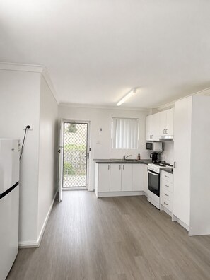 A modern kitchen with white cabinets, a built-in oven, and a microwave.