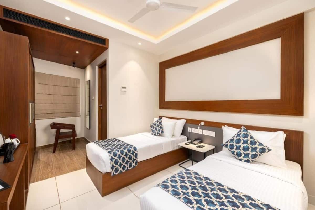 A hotel room with two beds, a desk, a chair, and a large window.