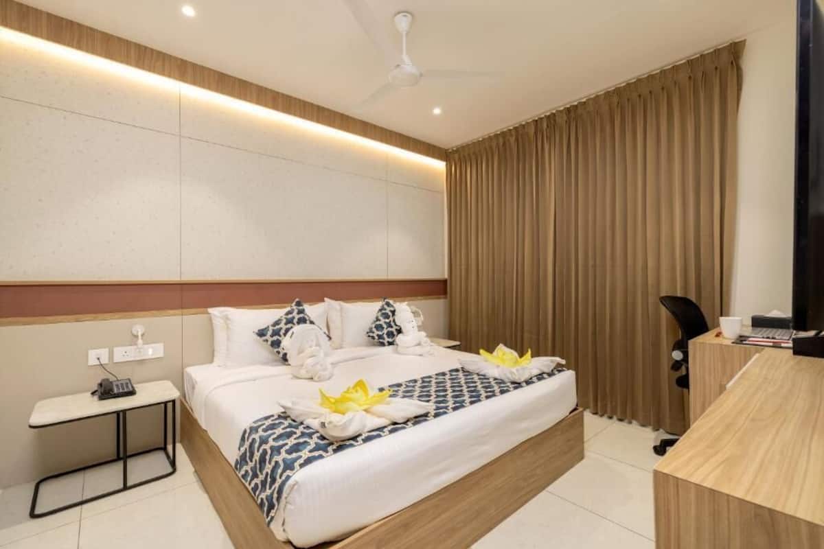 A hotel room with a bed, bedside table, desk, and a television.