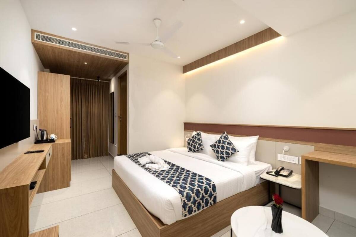 A modern hotel room with a bed, bedside table, TV, and a desk.