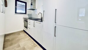 A modern kitchen with white cabinets, a black countertop, and stainless steel appliances. - Business Apartment Wangen (Wangen an der Aare)