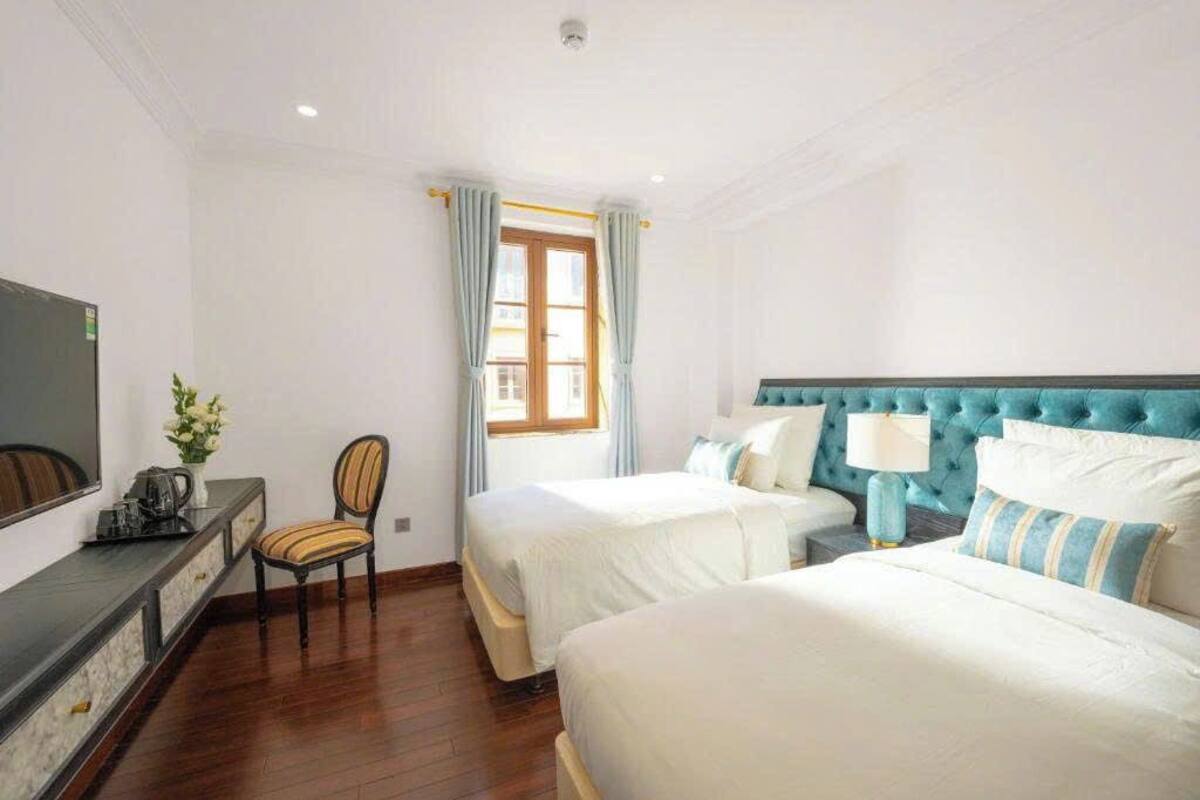 Une chambre d’hôtel avec deux lits, une télévision, un bureau et une chaise.