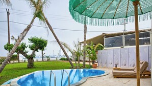 A swimming pool with a green umbrella, lounge chairs, and a view of the ocean. - Le Palme Beach Rhodes- Pool Heart Villa (Χαράκι)