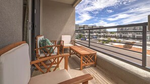 En balkon med to træstole og et lille bord, med udsigt over et moderne boligkompleks.
