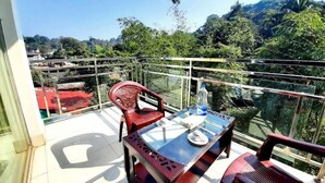 A balcony with a glass table, two chairs, and a bottle of water. - Hotel Grand Valley (Bandarban)