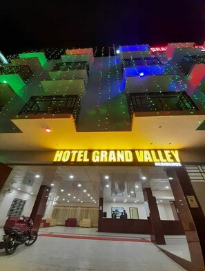 Exterior del Hotel Grand Valley con una entrada destacada y una motocicleta estacionada afuera.