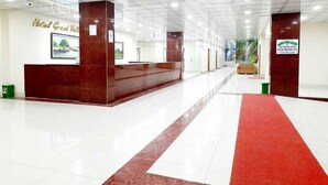 A hotel reception area with a marble reception desk, a red carpet, and framed pictures on the walls. - Hotel Grand Valley (Bandarban)