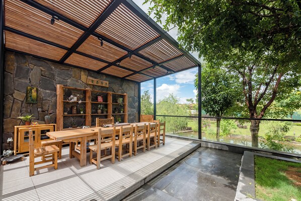 Un comedor de madera con pared de piedra y vistas a un jardín.