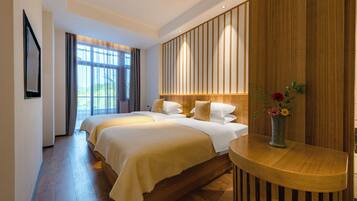 Habitación de hotel con una cama grande, cabecero de madera, mesita de noche con un jarrón de flores y vistas al exterior a través de la ventana.