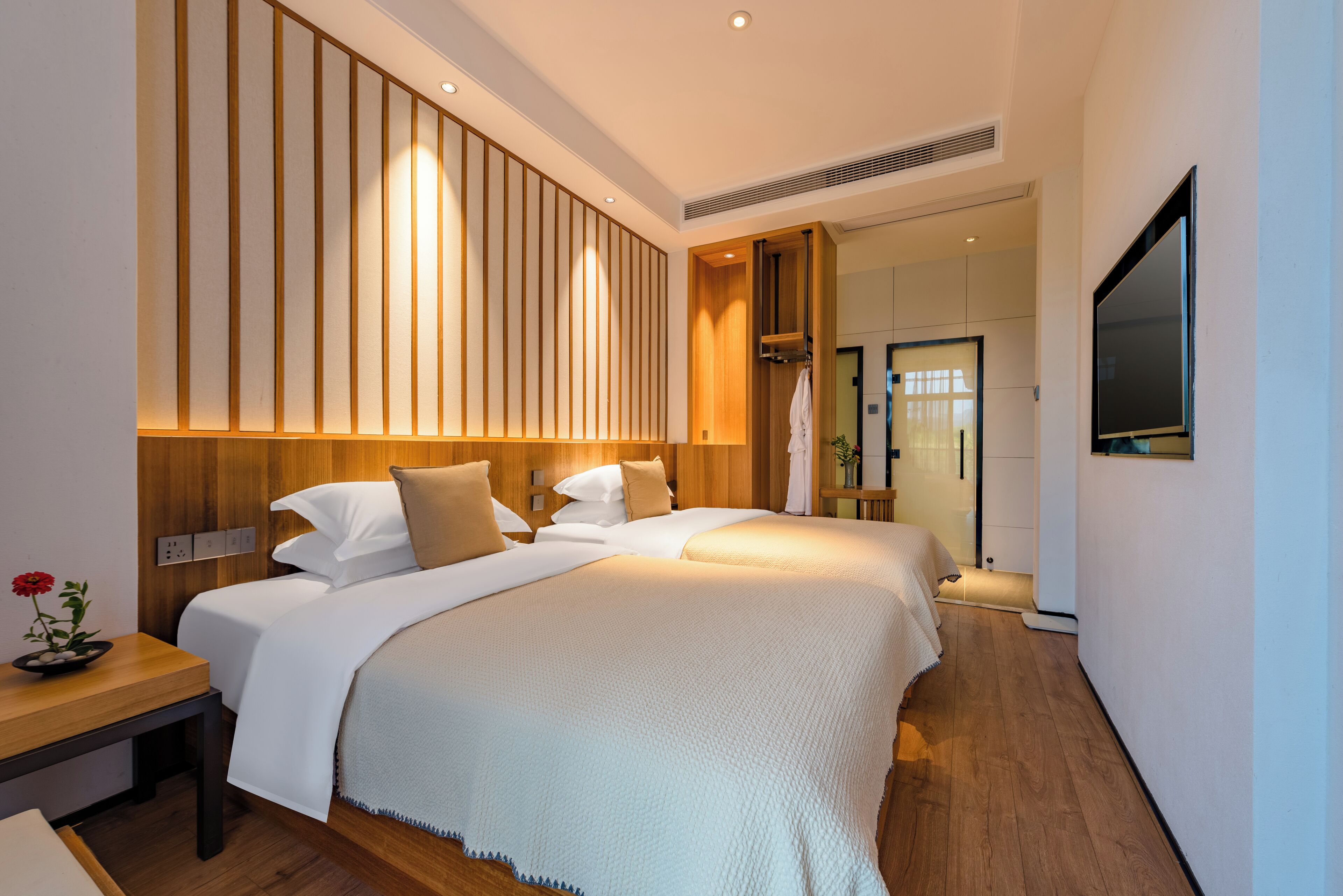 A modern hotel room with a large bed, bedside tables, and a TV mounted on the wall.