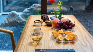 Une table en bois sur laquelle on trouve une variété de fruits, une fleur et une théière.