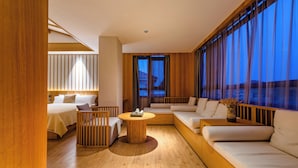 Une chambre d’hôtel moderne avec un lit, un canapé, une table basse et de grandes fenêtres.