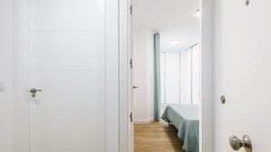 Un pasillo con una cama y una puerta de baño.