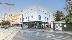 Un edificio moderno con fachada de vidrio, una línea de tranvía y un paso de peatones.