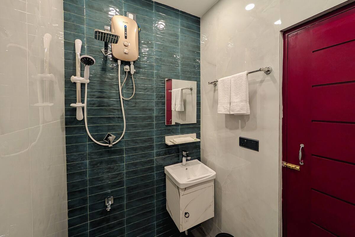 A bathroom with a shower, a sink, and a red door.