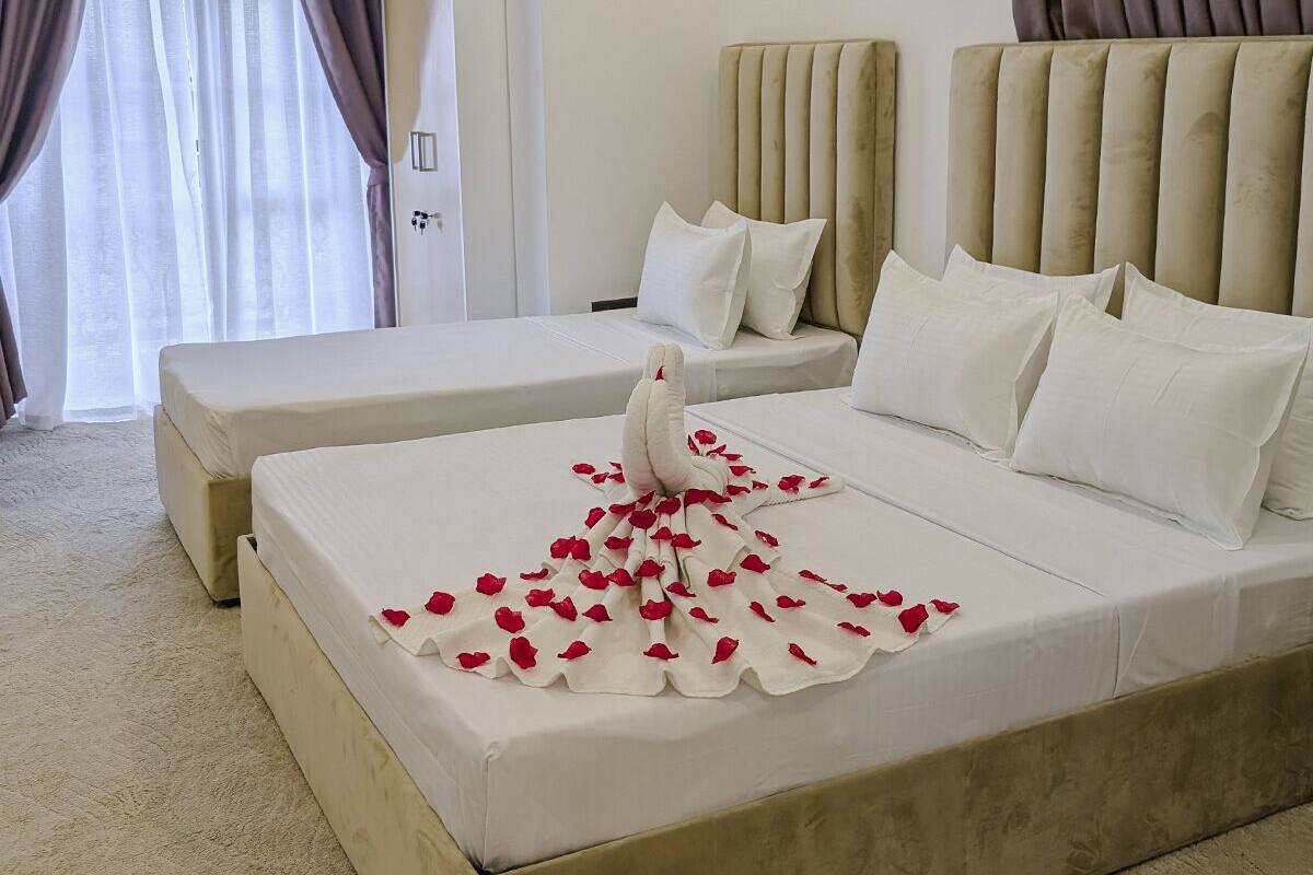 A hotel room with a large bed, a smaller bed, and a separate seating area.
