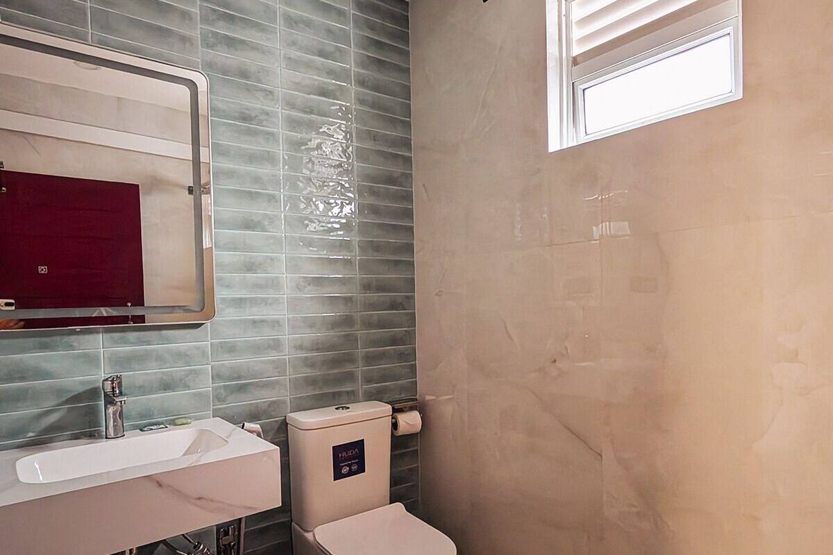 A modern bathroom with a white sink, mirror, and toilet.