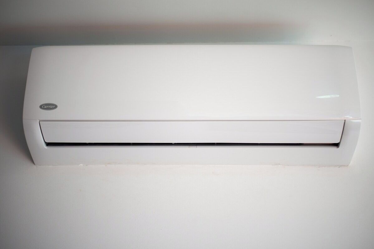 Een witte, aan de muur bevestigde airconditioner met een zichtbaar logo.