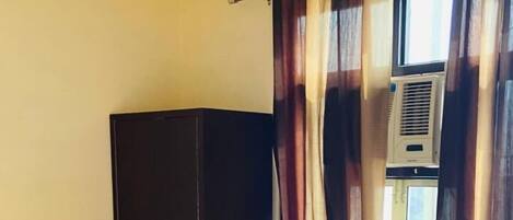 A bedroom with a bed, a wardrobe, and an air conditioning unit.