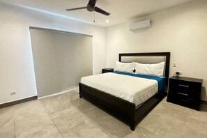 A bedroom with a bed, a nightstand, a ceiling fan, and an air conditioning unit.