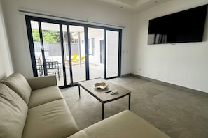 Ein Wohnzimmer mit einer Couch, einem Couchtisch und einer Schiebetür zu einem Außenbereich mit Sitzgelegenheiten.