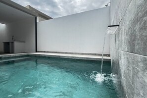 An indoor swimming pool with clear water, a modern architectural design, and a minimalist aesthetic.