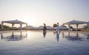 A pool area with two white gazebos and a person walking. - Prime Desert Camp - Jaisalmer (Jaisalmer)