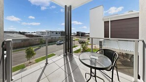 A balcony with a glass railing, a table, and chairs. - Griffin Family Stay – 4BR Modern Home (Griffin)