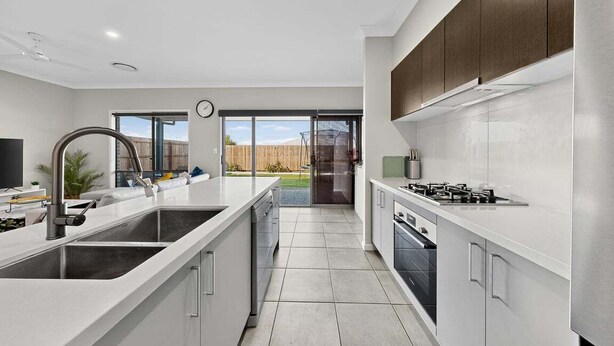 A modern kitchen with white countertops, stainless steel appliances, and a large window offering a view of the outdoors. - Griffin Family Stay – 4BR Modern Home (Griffin)