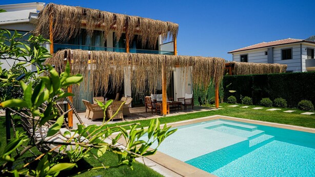 Une maison moderne dotée d’une piscine, d’un espace salon extérieur abrité et d’une pelouse bien entretenue.