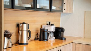 Une cuisine équipée d’un plan de travail en bois, d’une machine à café, d’une bouilloire et d’un grille-pain.