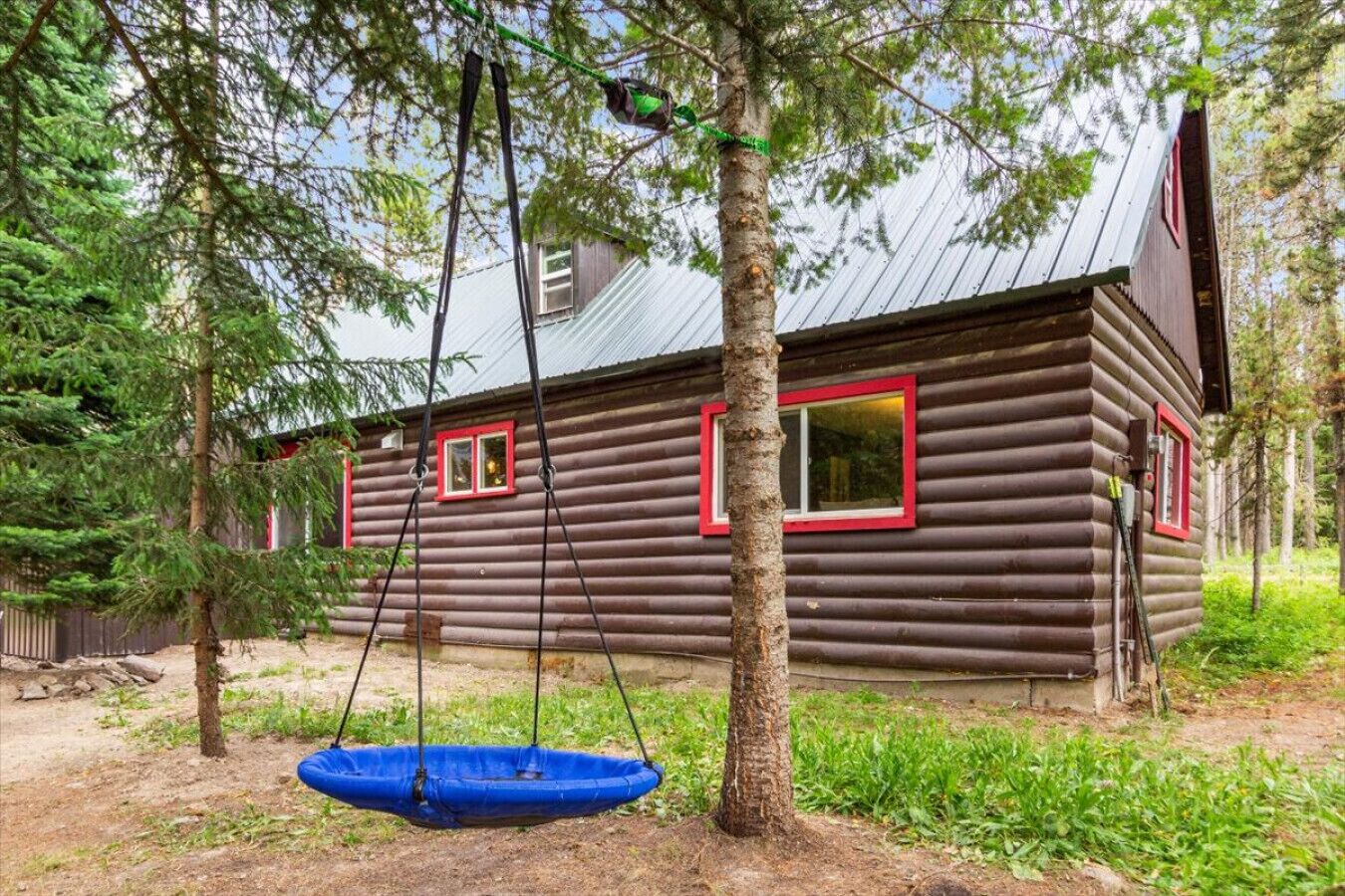 A rustic log cabin with a swing chair and a small blue pond in front.