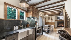 A modern kitchen with a large island, a fireplace, and a dining area.