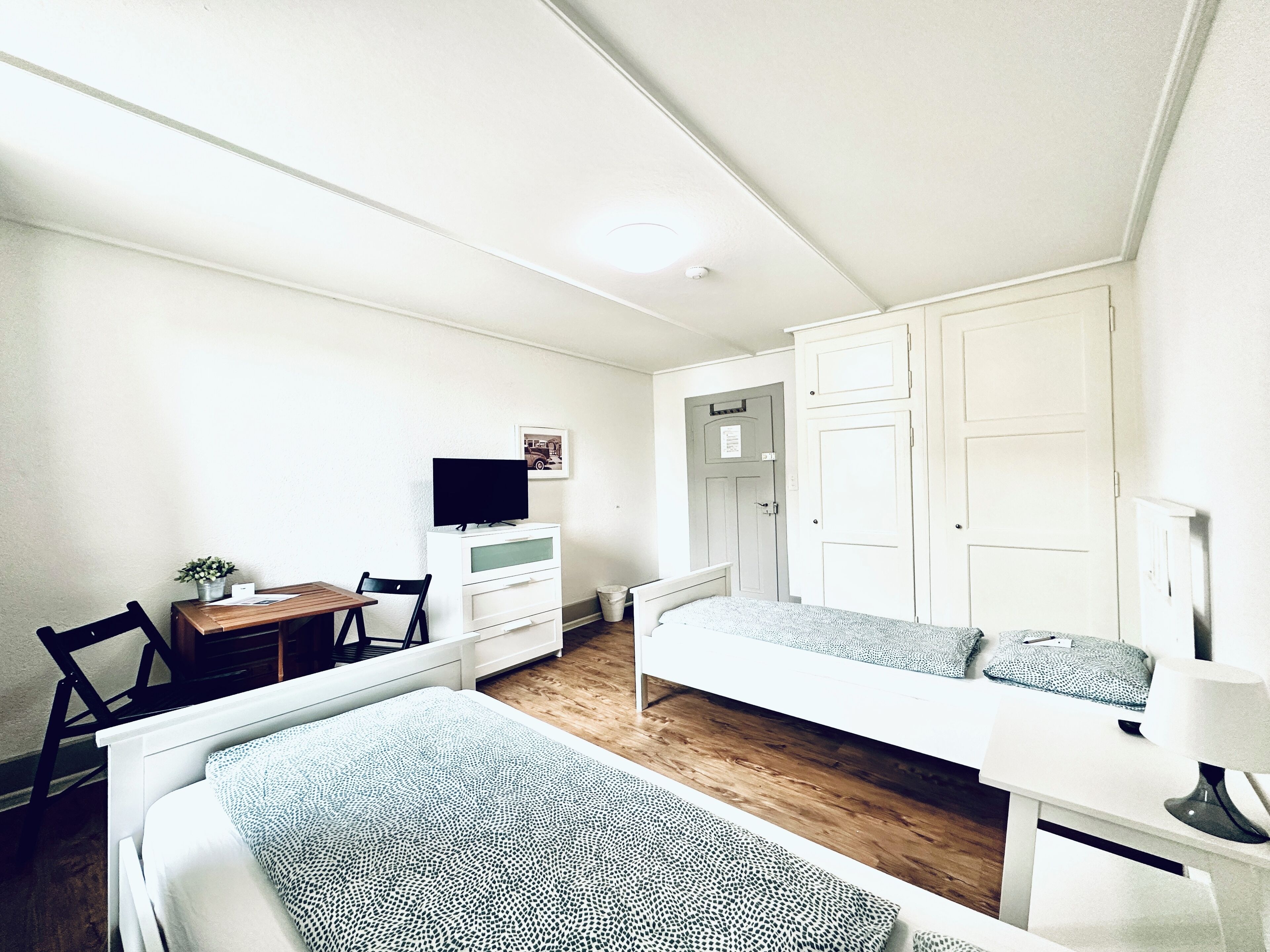 Una habitación pequeña y bien iluminada con cama, escritorio, silla y televisor.