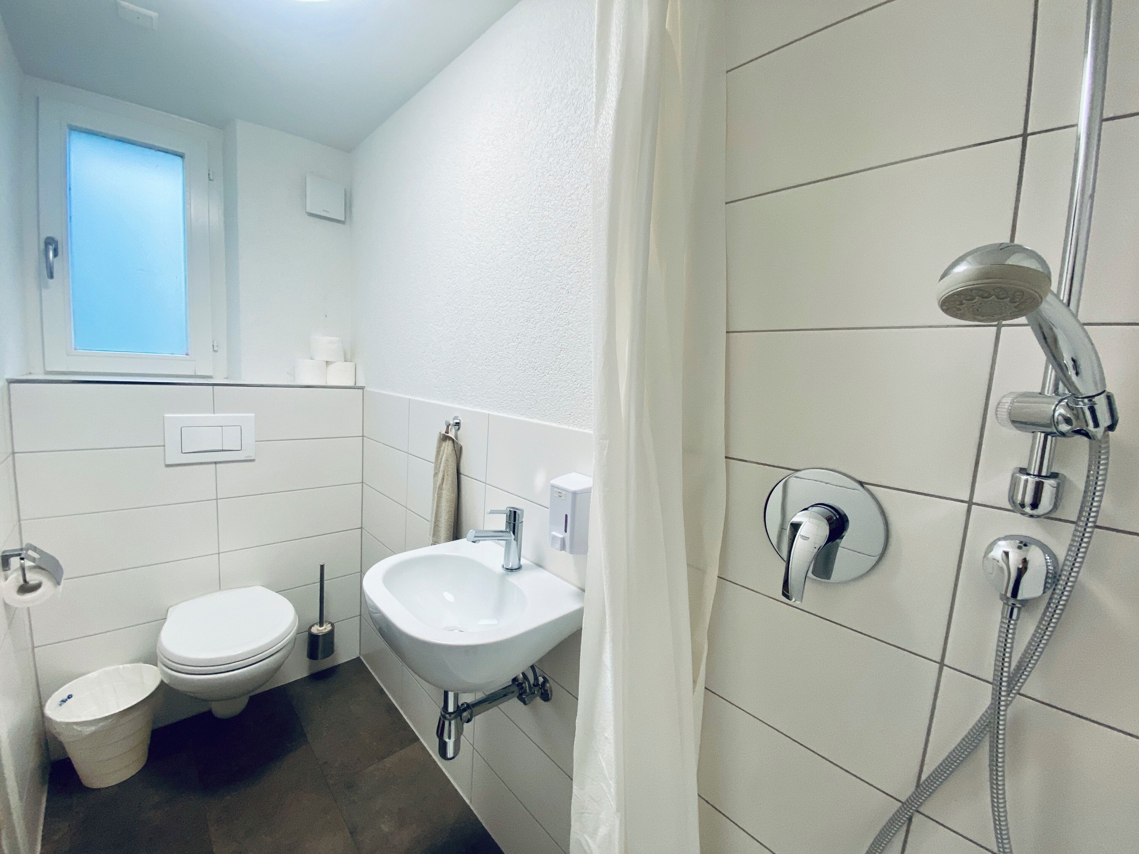 Ein modernes Badezimmer mit Toilette, Waschbecken und Dusche.