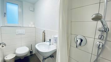 Ein modernes Badezimmer mit Toilette, Waschbecken und Dusche.