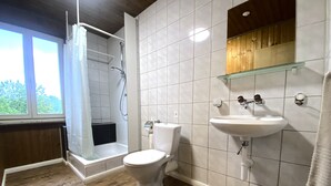 A bathroom with a shower, toilet, sink, and wooden flooring. - ZIMMERzuVERMIETEN.ch Biberist (Biberist)