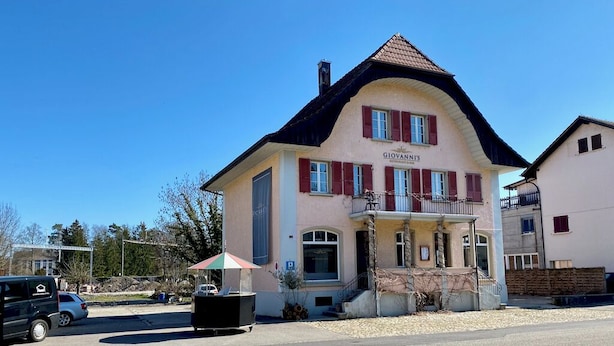 A two-story building with a balcony, a sign reading "GIOVANIS," and a parked car in front. - ZIMMERzuVERMIETEN.ch Biberist (Biberist)