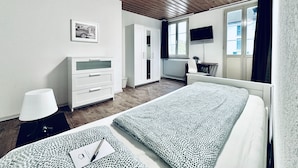A bedroom with a bed, a dresser, a desk, a chair, a TV, and a window. - ZIMMERzuVERMIETEN.ch Biberist (Biberist)