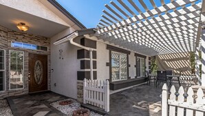 A covered patio area with a pergola, a white picket fence, and a stone-tiled patio. - Spacious 5-bedroom house in delightful Glendale with WiFi, AC (Glendale)