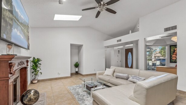 A spacious living room with a large sofa, a coffee table, and a fireplace. There is a ceiling fan and a large window with a view of the outside. - Spacious 5-bedroom house in delightful Glendale with WiFi, AC (Glendale)