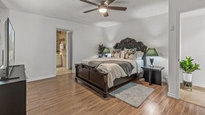 A bedroom with a wooden bed, a ceiling fan, a nightstand with a lamp, and a potted plant. - Spacious 5-bedroom house in delightful Glendale with WiFi, AC (Glendale)