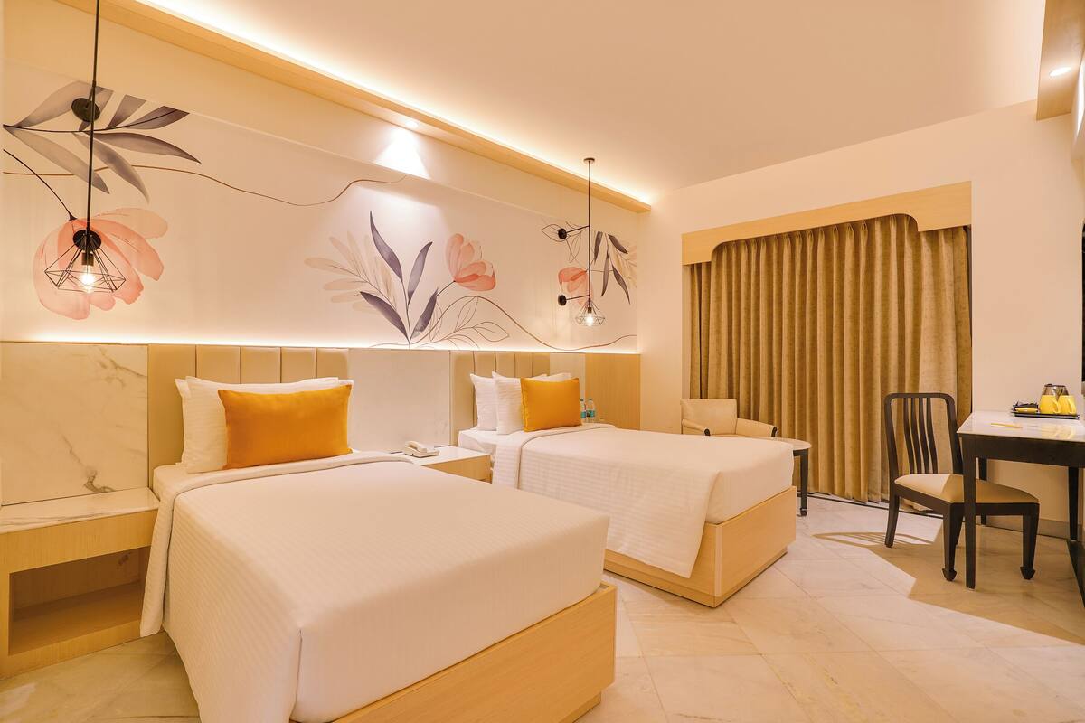 A hotel room with two beds, a desk, and a chair.