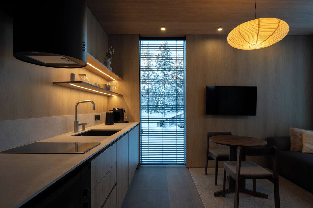 Una cocina moderna con estufa integrada, un lavamanos y un comedor con mesa y sillas.